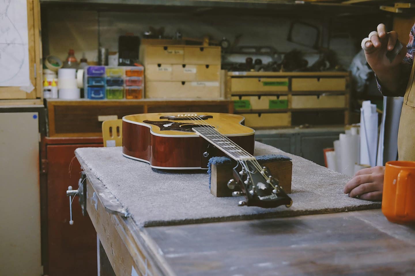 Chitarra acustica su un banco da lavoro in un negozio disordinato.