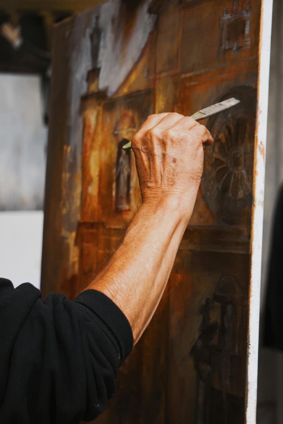 Artista che dipinge una facciata architettonica su tela.