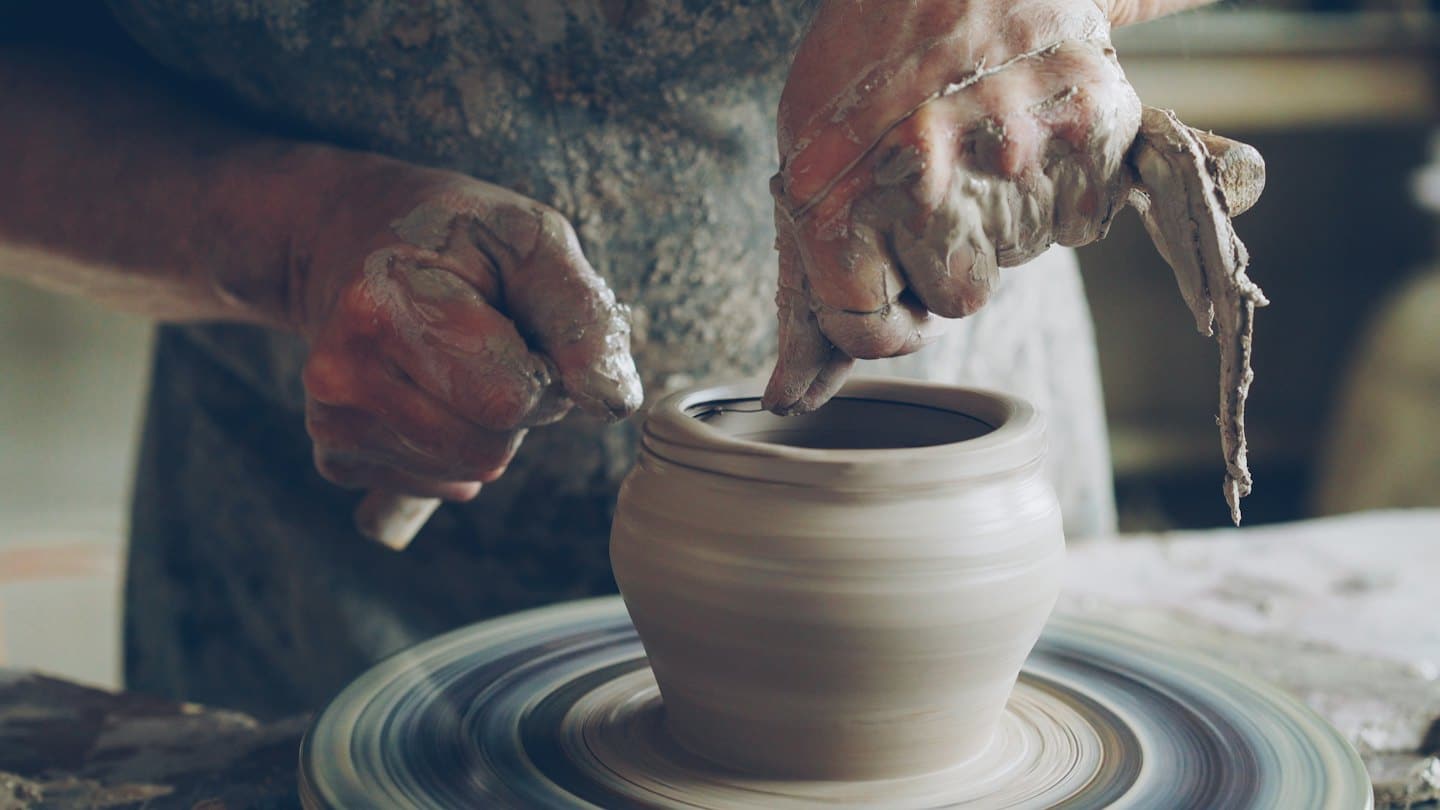 Mani modellano un vaso di argilla bagnata su un tornio.